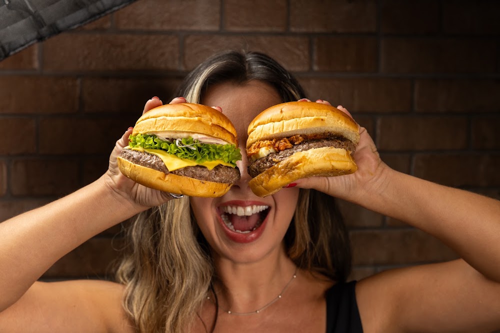 Cliente segurando dois burgers do BBJ